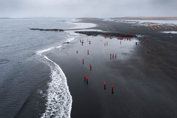 Am Reynisfjara Strand in Island laufen Gäste der Kreuzfahrt über den schwarzen Strand